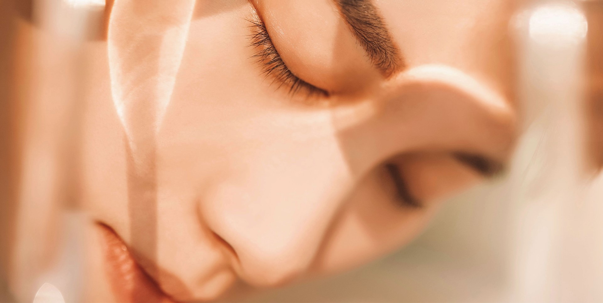 Primer plano en enfoque suave del rostro de una mujer joven con los ojos cerrados, la piel resplandeciente y expresión apacible.