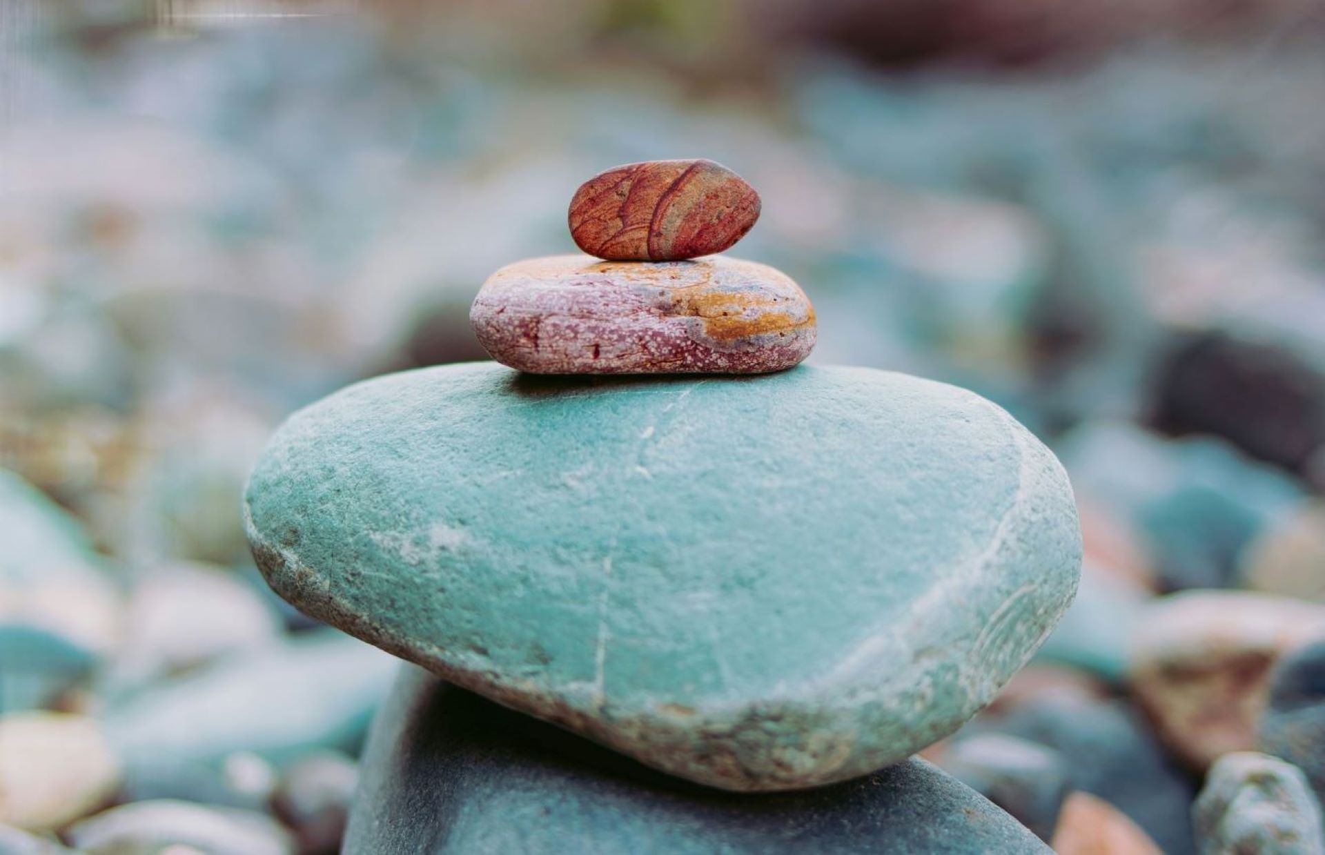 一摞由浅绿色与棕色石头平衡堆叠而成的石堆，彰显着稳定与自然之美。