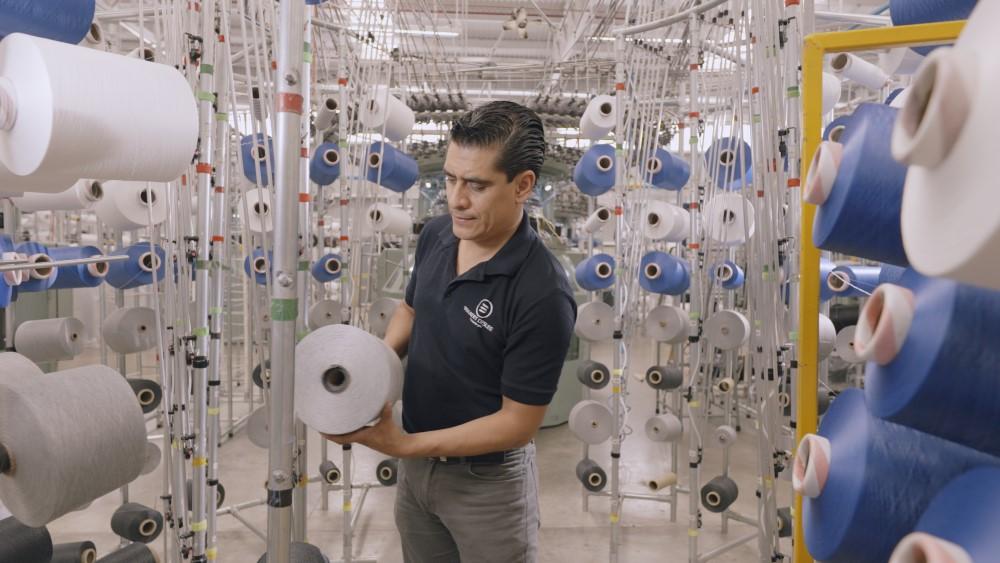 BekaertDeslee employee handling large spools of thread in a BekaertDeslee factory