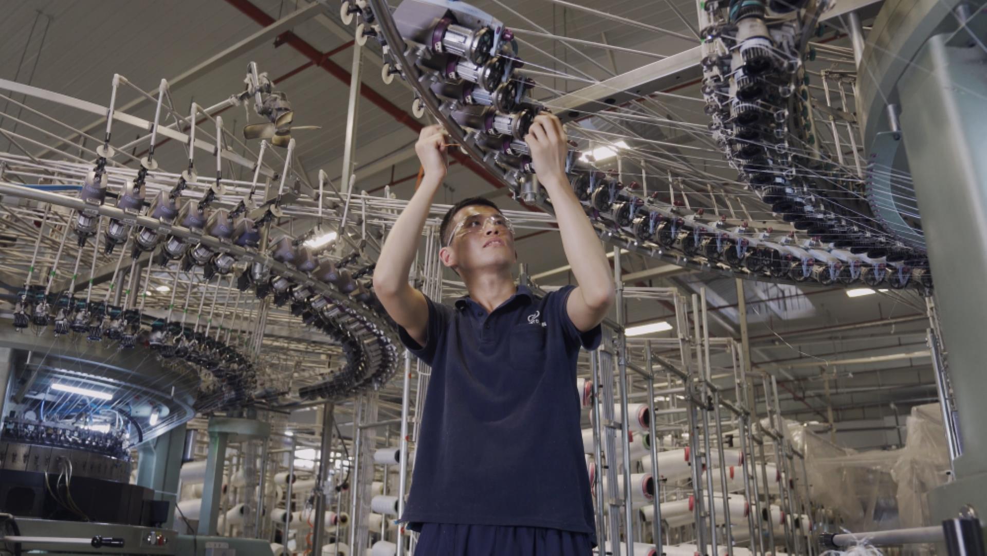 Skilled employee adjusting a textile machine and ensuring the production quality in a BekaertDeslee mattress fabric manufacturing facility.