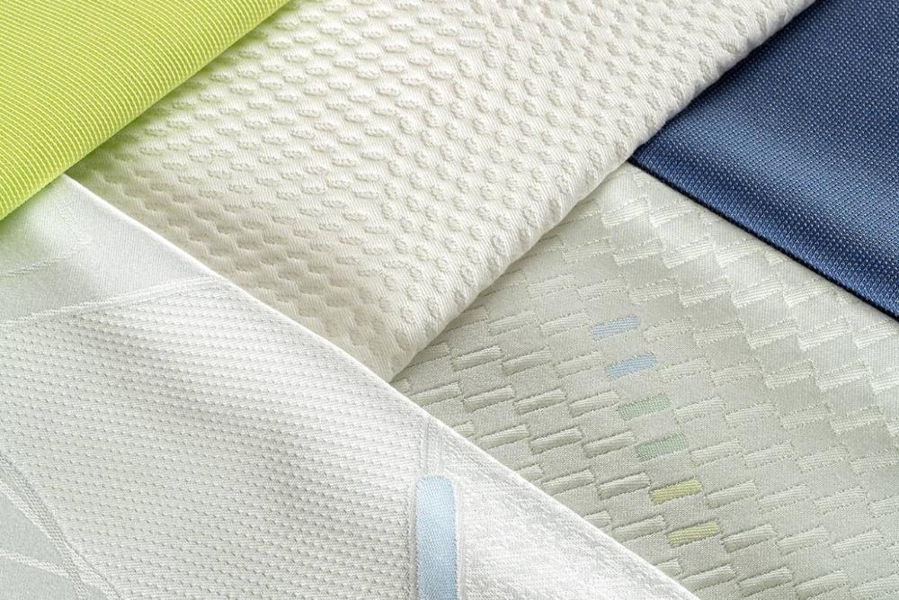 close-up of white mattress fabric samples with textured patterns and a green highlight