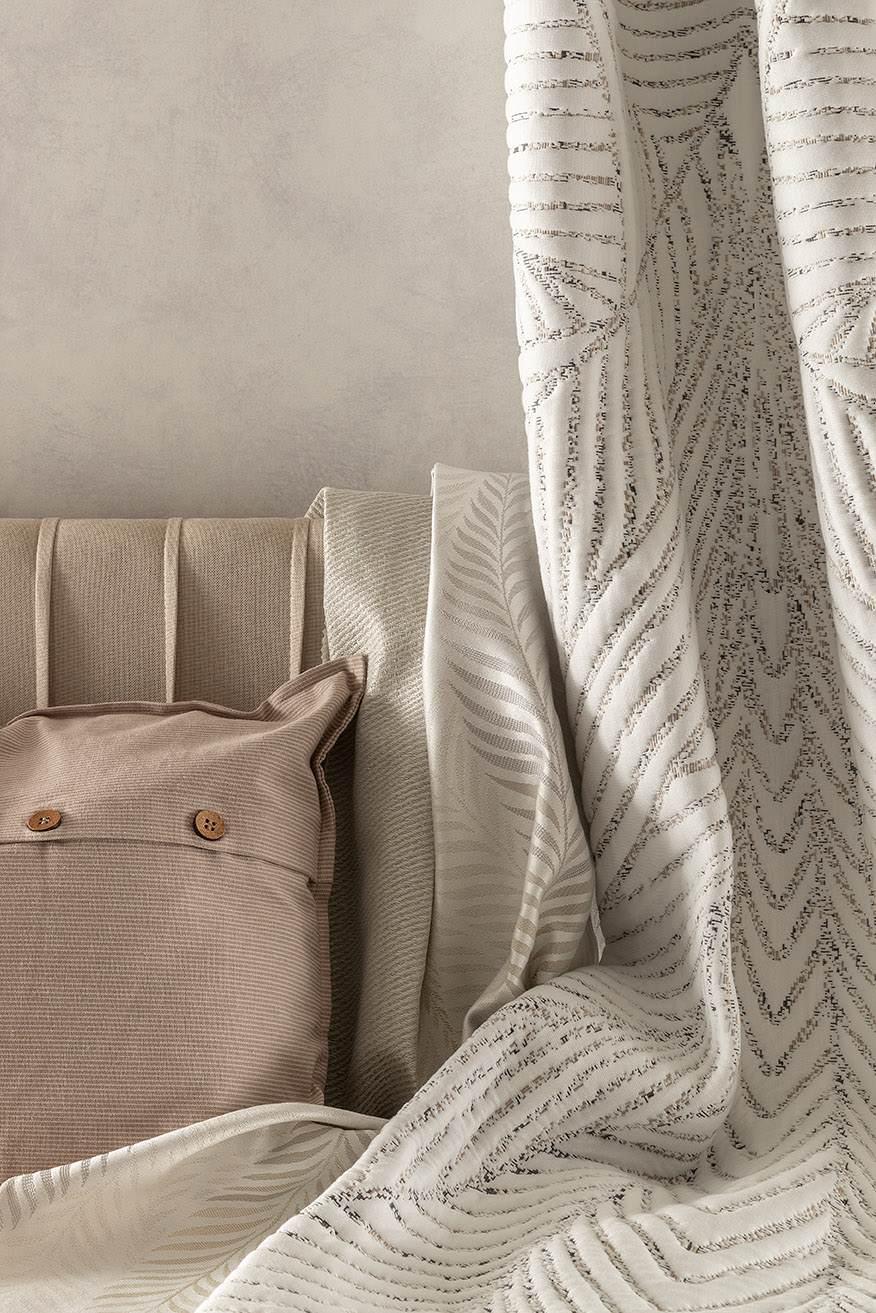Beige and cream mattress fabrics with soft, linear patterns on a cushioned bed headboard
