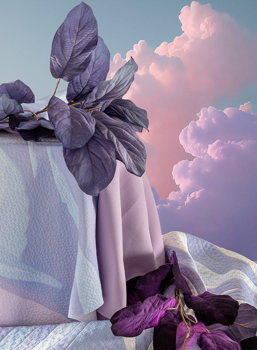 Dreamy artistic display of soft purple mattress fabrics adorned with dark purple leaves against a pink clouded sky