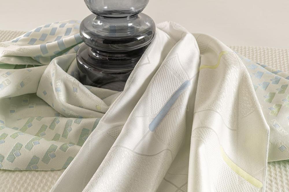 Elegant white patterned mattress fabrics artistically draped around a dark glass lamp