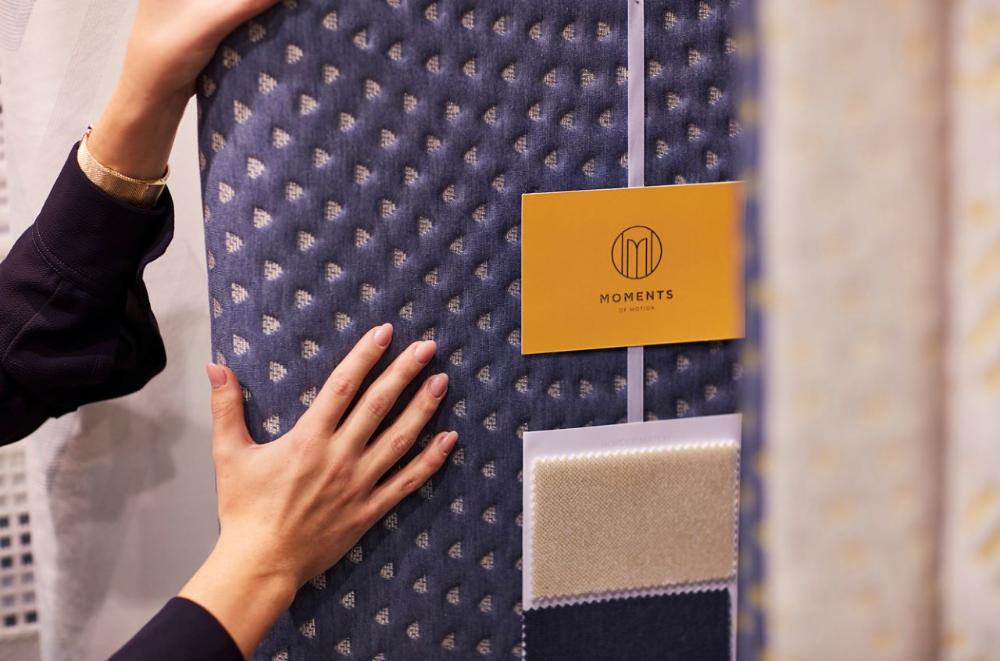 Textured blue fabric on a panel supported by hands of BekaertDeslee employee