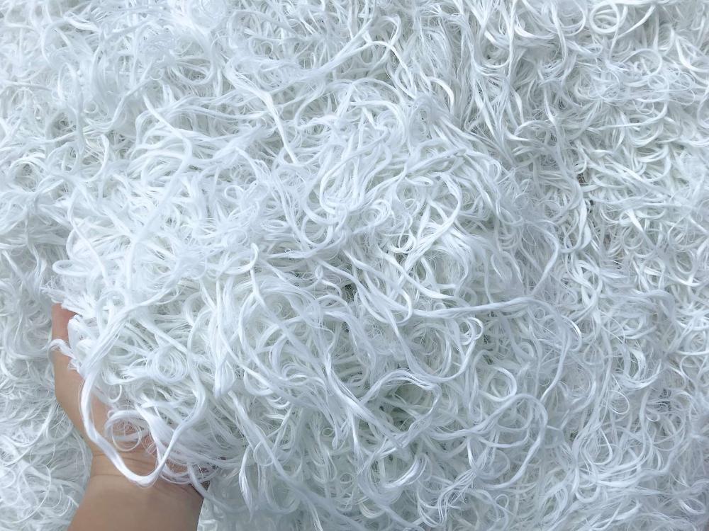 Densely packed glossy white fibers, soft and tangled, made of post-production waste.